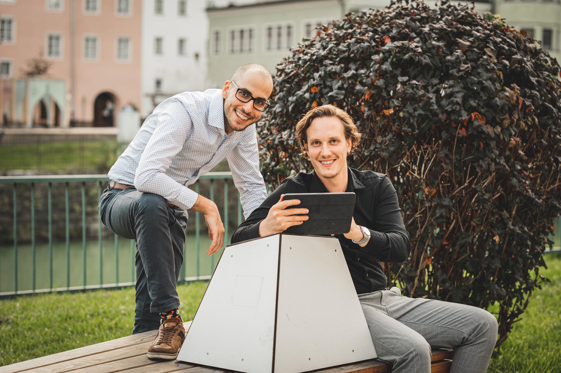 Thomas Steiner und Tobias Franek auf einer Bank in mit Blick in die Kamera