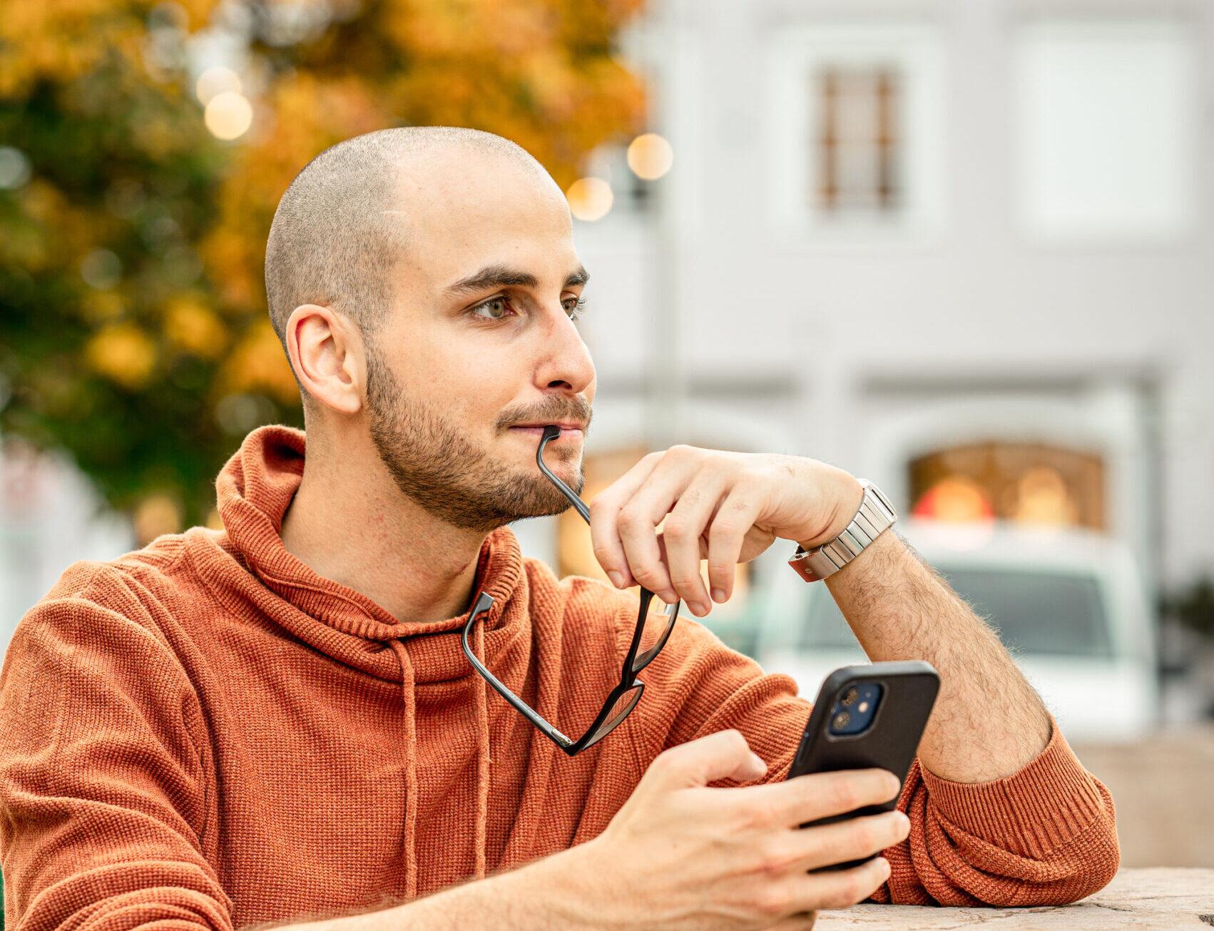 Tobias Franek nachdenklich mit dem Handy in der Hand.